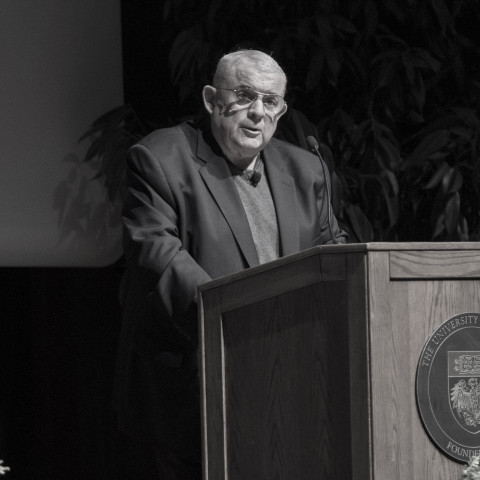 Prof. Dennis J. Hutchinson speaks at a podium with the UChicago seal on it.